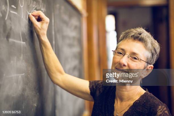 friendly senior female mathematics teacher bij chalkboard - vrouwelijke gestalte stockfoto's en -beelden