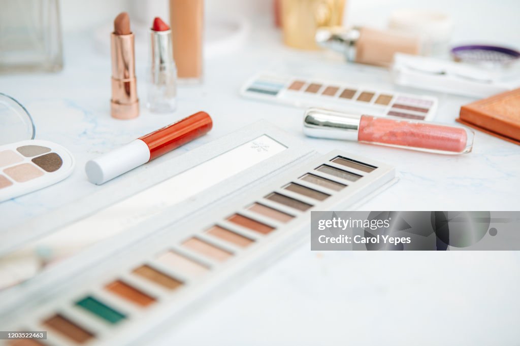 Pile of various cosmetics, make-up lie on wooden dressing table
