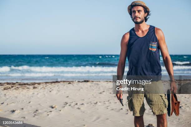 de knappe kerel met hoed is op het strand - hemden stockfoto's en -beelden