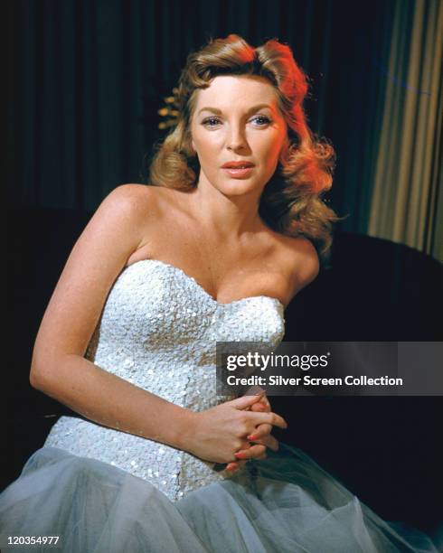Julie London , US singer and actress, wearing a dress with a silver bodice, in a studio portrait, circa 1955.