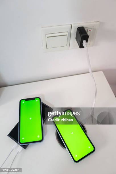 two phones are charging with a wireless charger - basso foto e immagini stock