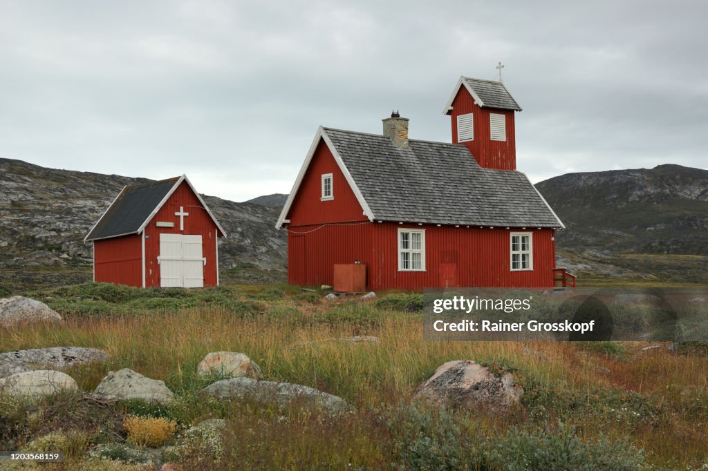 A little red wooden church in an arctic landscape with cloudy sky