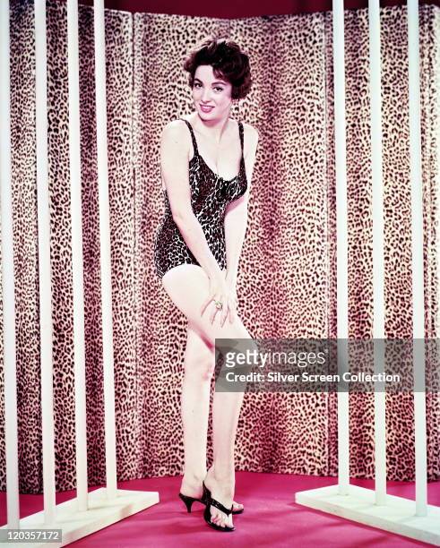 Linda Cristal, Argentine actress, wearing a leopard print swimsuit, while posing in front of a leopard print curtain in a studio portrait, 1958.