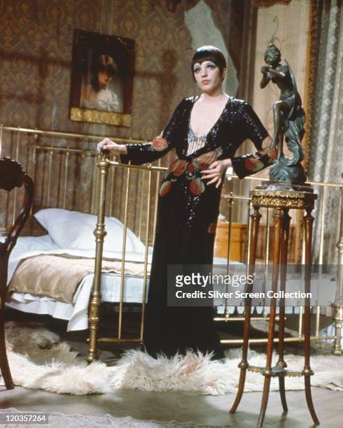 Liza Minnelli, US actress and singer, wearing a low-cut, long black dress, posing beside a bed in a publicity still issued for the film, 'Cabaret',...
