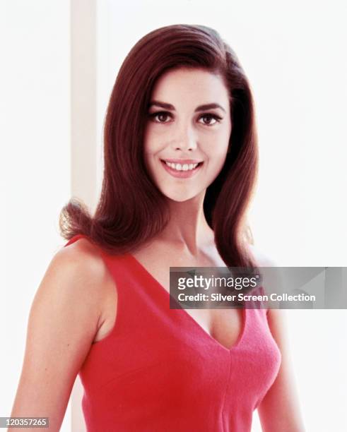 Linda Harrison, US actress and model, smiling, wearing a pink vest top, in a studio portrait, against a white background, circa 1965.