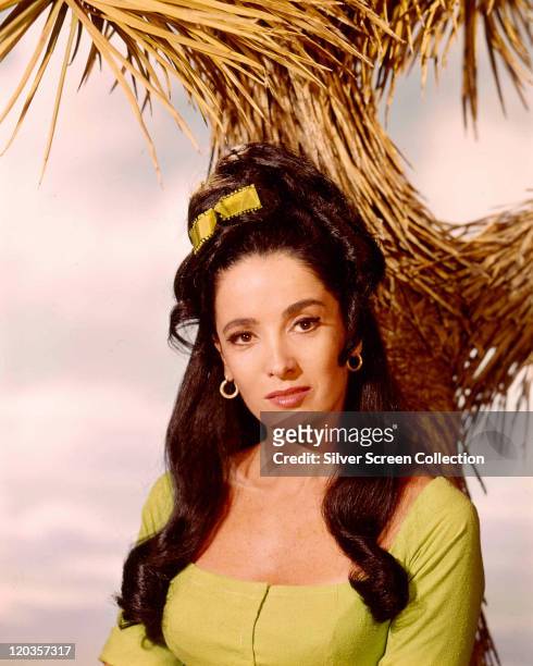 Linda Cristal, Argentinian actress, with a yellow bow in her hair, in a studio portrait, against a background of straw, issued as publicity for the...