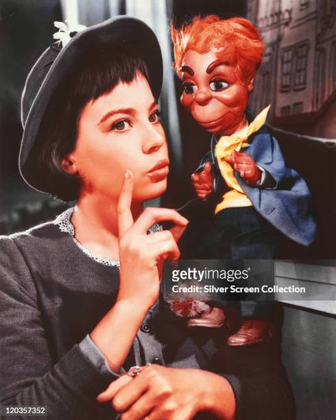 Leslie Caron, French actress, wearing a grey jacket and matching hat, posing beside a puppet in a publicity still issued for the film, 'Gigi', 1958....