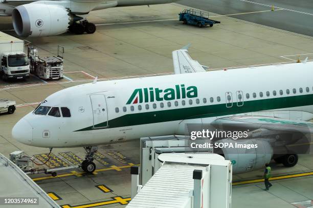 An Alitalia airlines Airbus A320 aircraft parked at a gate at London Heathrow Airport.