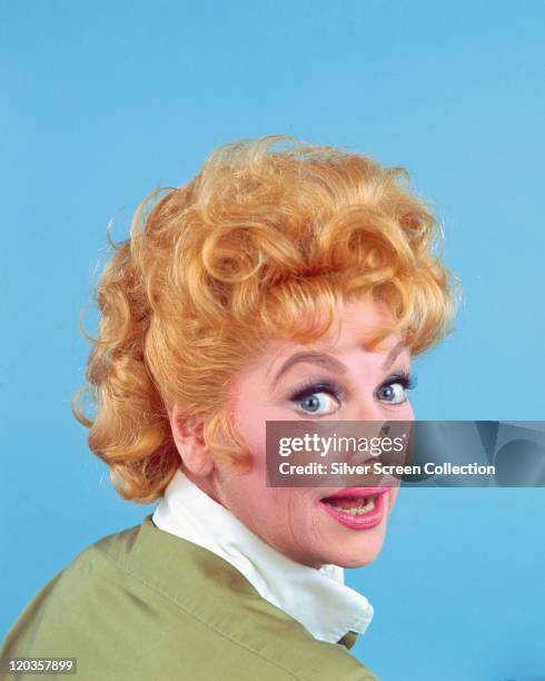 Headshot of Lucille Ball , US actress and comedian, looking over her right shoulder, in a studio portrait, against a blue background, circa 1955.
