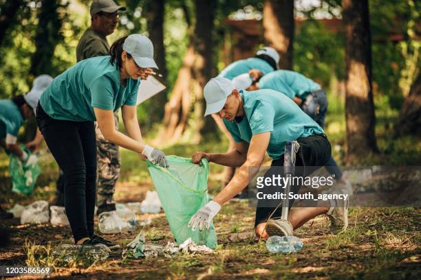 volunteers cleaning garbage together in park - disability collection stock pictures, royalty-free photos & images