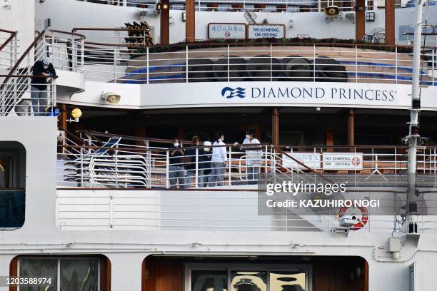This picture taken on February 24, 2020 shows crew members aboard the Diamond Princess cruise ship at the Daikoku Pier Cruise Terminal in Yokohama...