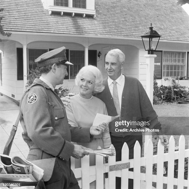 Post man delivering mail to senior couple, smiling