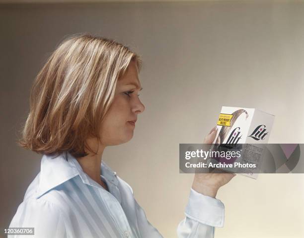 Young woman reading hair dye box, close-up