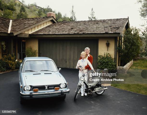 Couple standing with Puch moped and Honda Civic, smiling