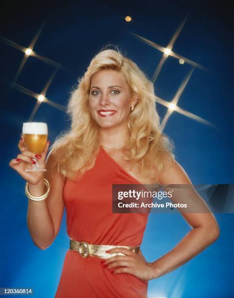 Young woman holding beer glass, smiling, portrait