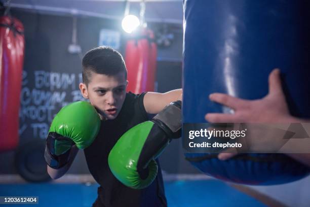 jonge kickbox vechter oefeningen blaast op de peer - kids boxing stockfoto's en -beelden