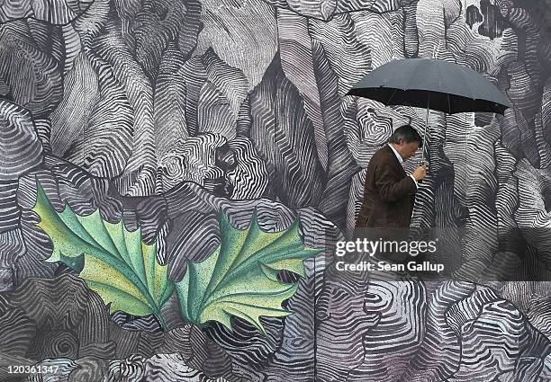 Peter Schwenkow, CEO and Chairman of DEAG, walks with an umbrella under rain on the set for the Seefestspiele 2011 music festival ahead of the...