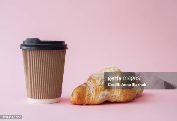 take away coffee in paper cup and croissant over pink background - coffe to go stockfoto's en -beelden