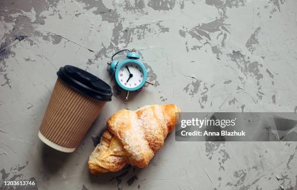 take away coffee in paper cup, retro alarm clock and croissant over pink background - coffee take away cup simple imagens e fotografias de stock