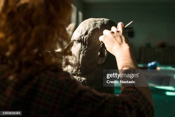 jeune femme rousse sculptant la tête hors de l’argile - moulant photos et images de collection