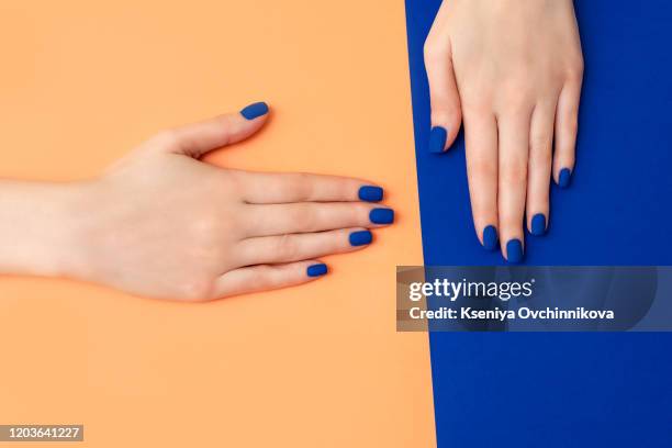 hand with artificial manicured nails colored with blue and orange nail polish on textile background - multi coloured nails stock pictures, royalty-free photos & images