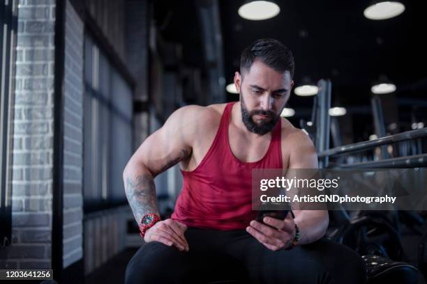 bodybuilder using smartphone in gym - form fitted stock pictures, royalty-free photos & images