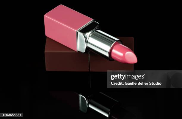 fashionable new pink lipstick on reflective black background - pink lipstick fotografías e imágenes de stock