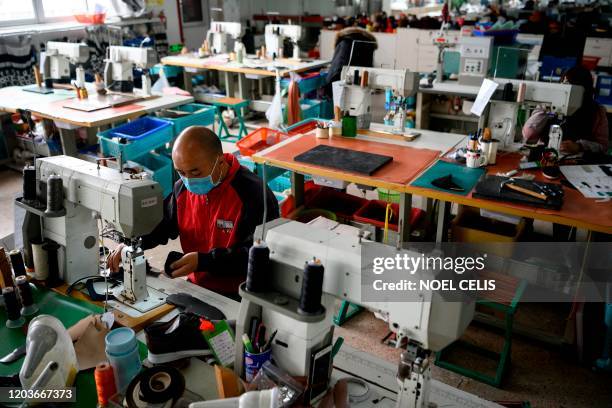 Workers wearing protective facemasks as a preventive measure against the COVID-19 coranavirus, sew shoe parts at the Zhejiang Xuda Shoes Co. Factory...