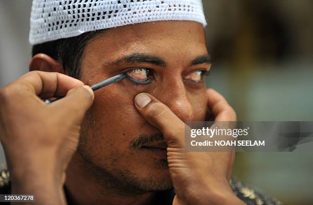 An Indian Muslims applies black Kajal to his eyes before praying on the first Friday of the month of Ramadan at the Bargahe Yousufain Sharifain...