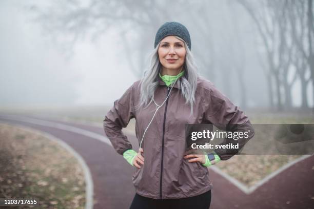 exercising woman at foggy day - mature woman winter stock pictures, royalty-free photos & images