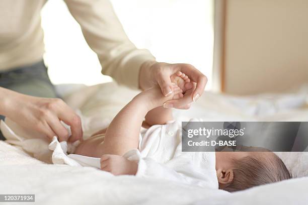 mother changing baby's diaper on bed - changing diaper ストックフォトと画像