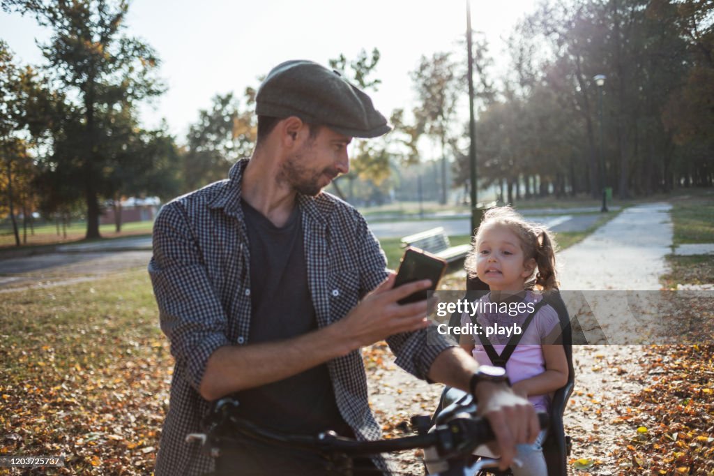 Vater fotografiert ihn und seine Tochter auf dem Fahrrad
