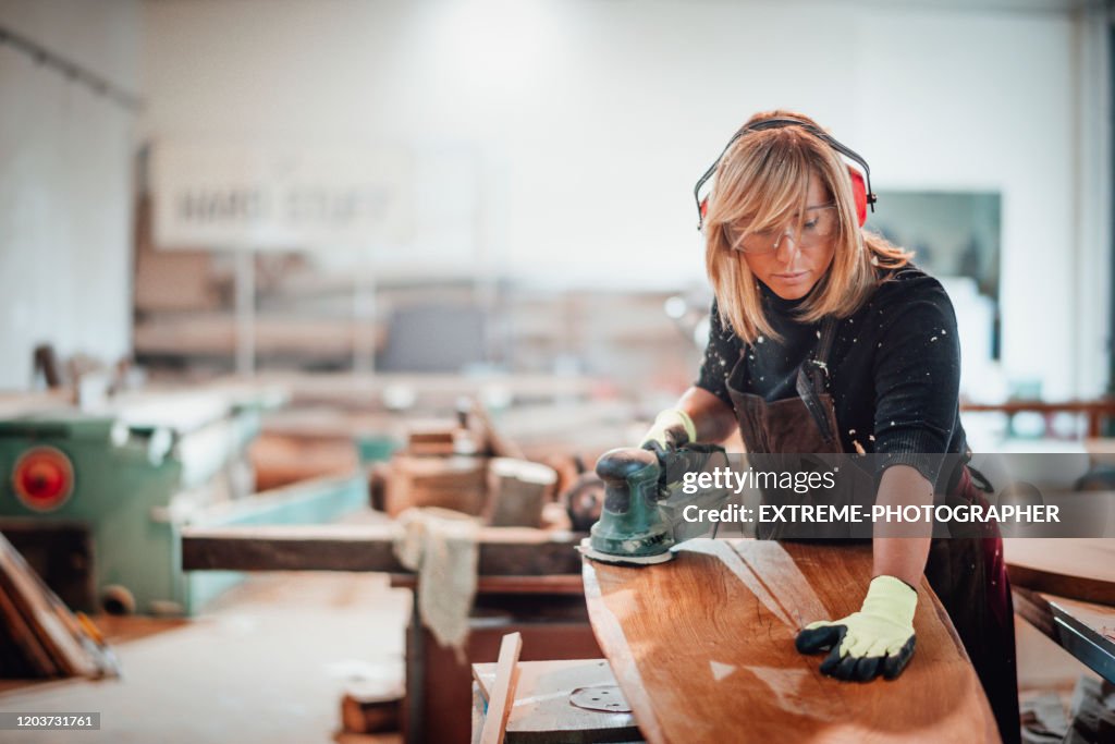 Woodworker using a hand sander to sand down a wooden surface