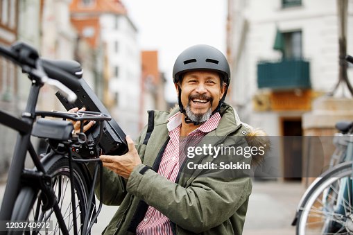 Senior man changing battery on electric bicycle Senior man changing battery on electric bicycle