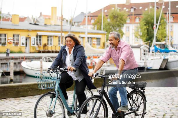 senior couple on electric bikes in old city area - oresund region 個照片及圖片檔