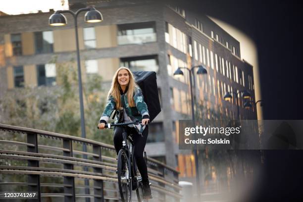 bicycle delivery woman with food backpack cycling in residential area - copenhagen food stock pictures, royalty-free photos & images