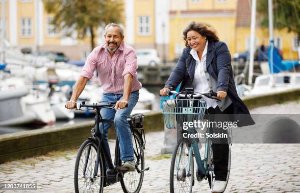 senior couple on electric bikes in old city area - oresund region 個照片及圖片檔