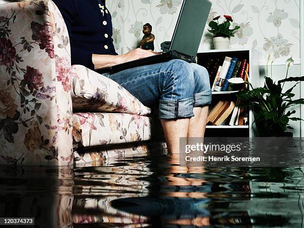 man in sofa in flooded room - huis overstroming stockfoto's en -beelden