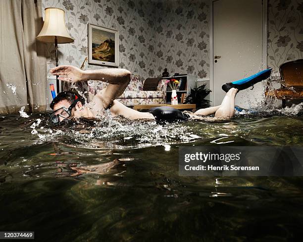 male swimmer in flooded living room - flooded room stock-fotos und bilder