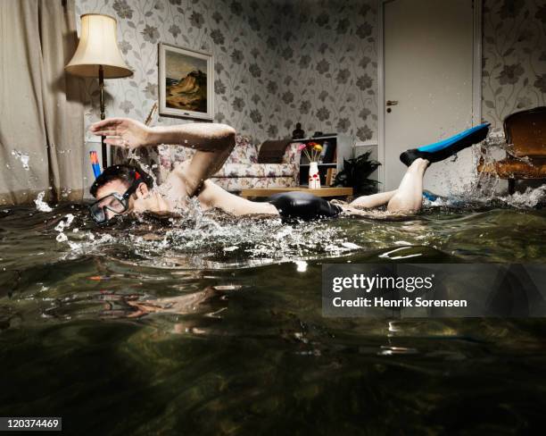 male swimmer in flooded living room - viaggio distruzione foto e immagini stock