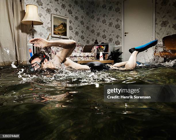 male swimmer in flooded living room - flooded room stock pictures, royalty-free photos & images