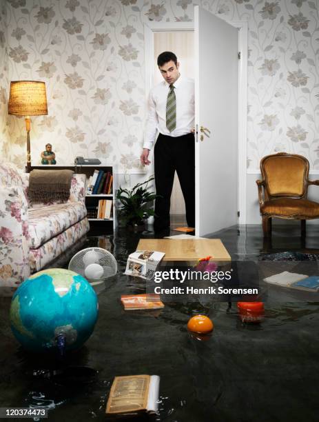 young man entering flooded livingroom - flooded room stock pictures, royalty-free photos & images