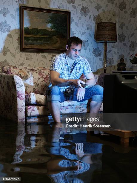 young man with tv in flooded room - flooded room stock-fotos und bilder