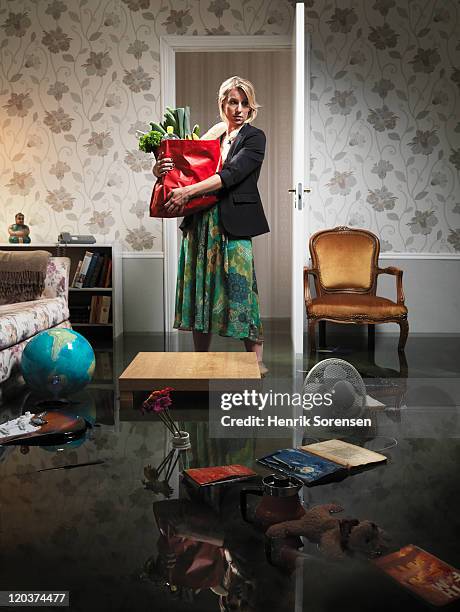 woman with grocery in flooded room - huis overstroming stockfoto's en -beelden