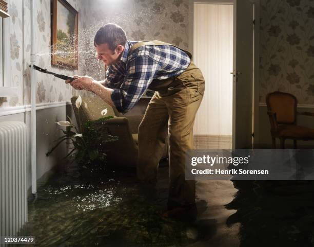 craftsman fixing pipe in flooded room - heraustropfen stock-fotos und bilder