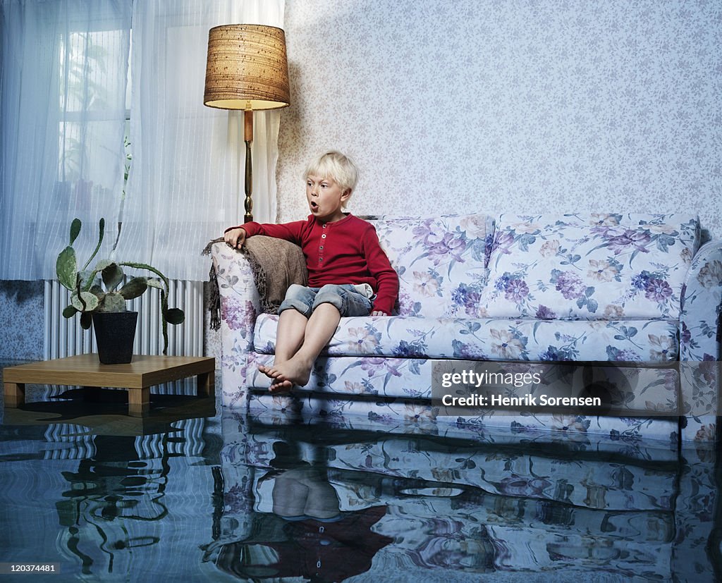 Young boy in sofa in flooded room