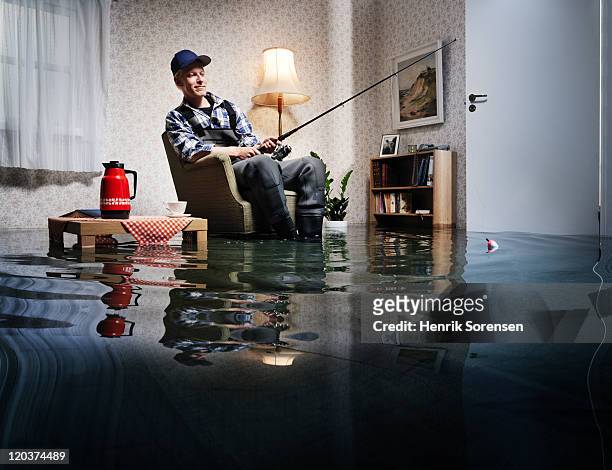 young man fishing in flooded room - flooded home stock-fotos und bilder