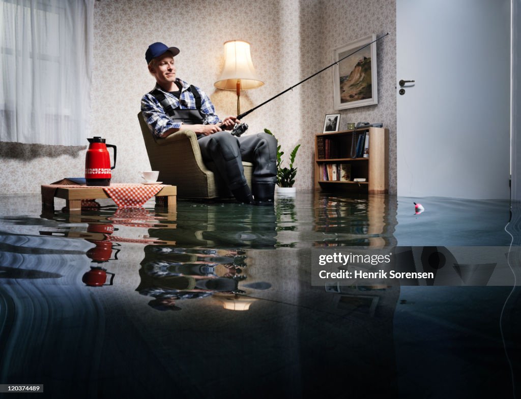 Young man fishing in flooded room