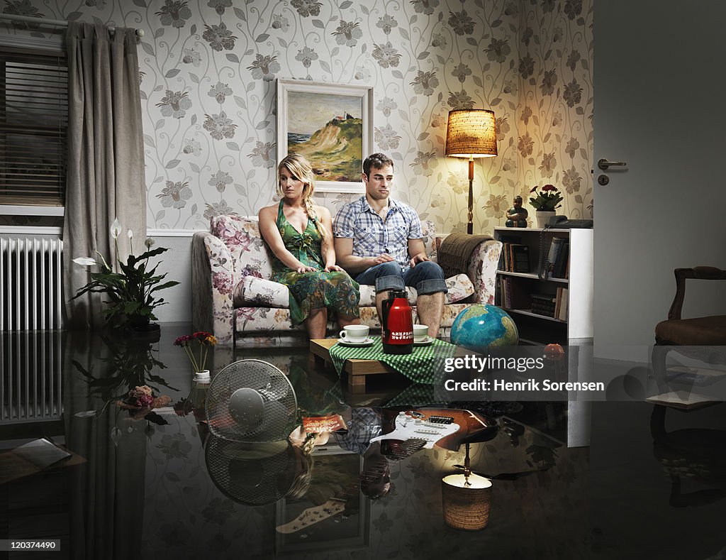 Young couple in sofa in a flooded room
