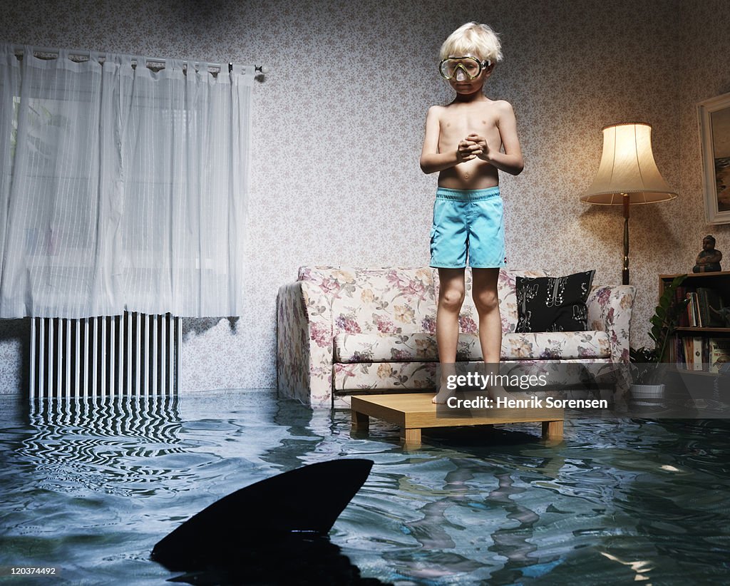 Boy on table in flooded room, with shark
